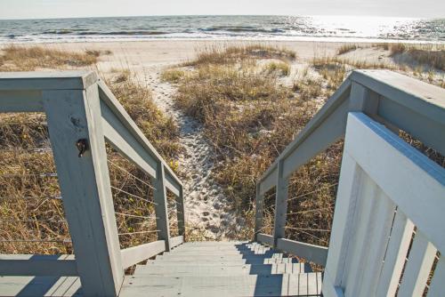 a staircase leading to a beach with the ocean at Fairwinds by Oak Island Accommodations in Caswell Beach