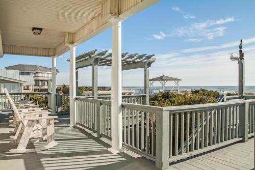 a porch with tables and chairs on the beach at Fairwinds by Oak Island Accommodations in Caswell Beach