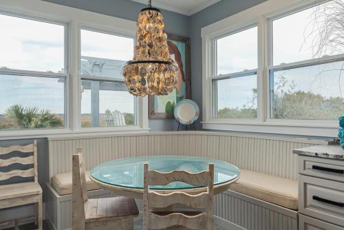 a dining room with a glass table and a chandelier at Fairwinds by Oak Island Accommodations in Caswell Beach