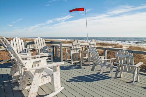 a deck with chairs and a flag on the beach at Fairwinds by Oak Island Accommodations in Caswell Beach