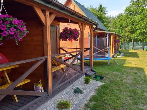 a wooden cabin with a porch and flowers on it at Domki i pokoje ,,Pod Palmami" w centrum in Okuninka
