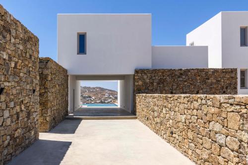 a stone wall separates a house from the ocean at Muro Suites in Ornos