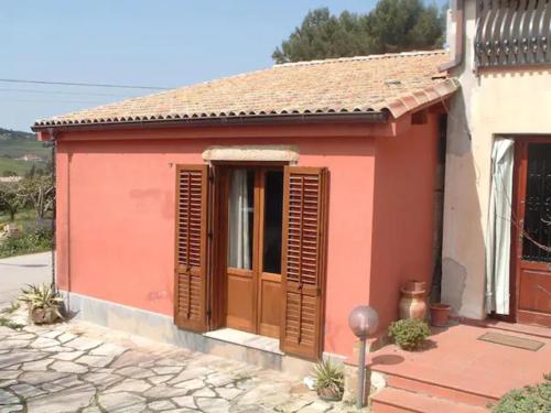 a small red house with wooden shutters at Rustico Zagara in Buseto Palizzolo