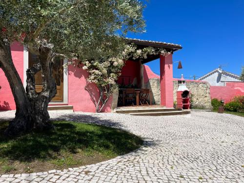 a tree in front of a pink house at Casa do Lagar - Villa com piscina in Carvalhais