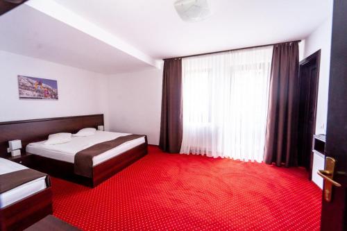 a bedroom with a bed and a red carpet at Pensiunea Campionilor in Predeal