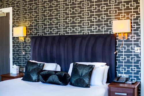 a bedroom with a bed with two black and white pillows at Cumberland Hotel - OCEANA COLLECTION in Bournemouth