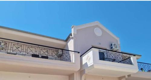 a white house with balconies and a blue sky at Xanthiotis Apartments in Skala Rachoniou