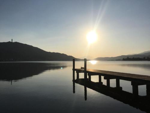 a dock on a lake with the sun in the sky at Appartement Wörthersee in Klagenfurt