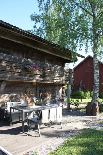 a wooden deck with a table and chairs in front of a barn at Willa Mustijoki in Laukkoski