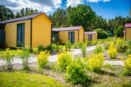 une rangée de maisons jaunes dans un jardin dans l'établissement Velo Camp nad jeziorem Dadaj, à Biskupiec