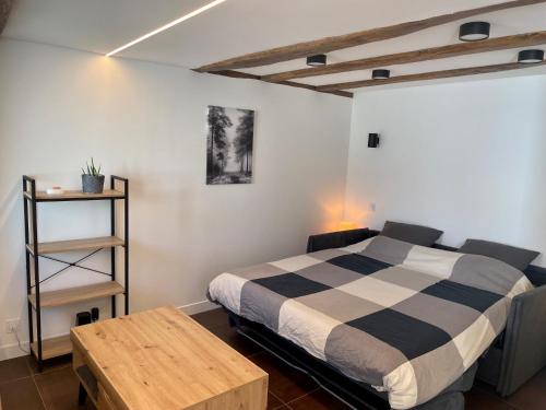 a bedroom with a black and white bed and a table at Studio de charme proche Nantes & aéroport au calme in Rezé