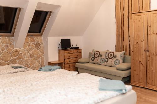 a bedroom with a bed and a couch and a chair at GRANÁRIUM in Jablonov nad Turnou