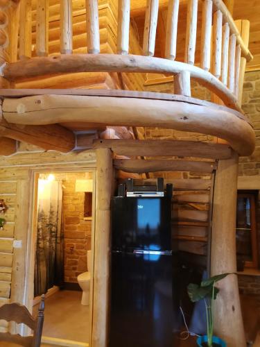 a loft bed in a log cabin with a tv at Cabana Casa de Piatra, de la Mara in Deseşti