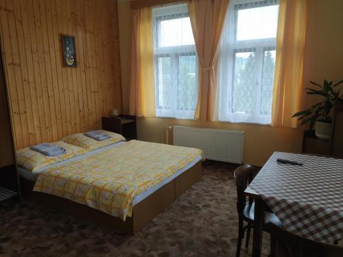 een slaapkamer met een bed en 2 ramen en een tafel bij Ubytování Na Kovárně in Smržovka