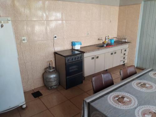 Il comprend une cuisine équipée d'un évier, d'une cuisinière et de chaises. dans l'établissement Casa em Olímpia, à Olímpia