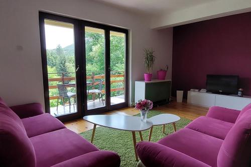 a living room with purple couches and a table at Villa Ramonda in Dolna Matka