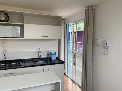 a kitchen with white cabinets and a window at Loft container central c/ estacionamento in Pelotas