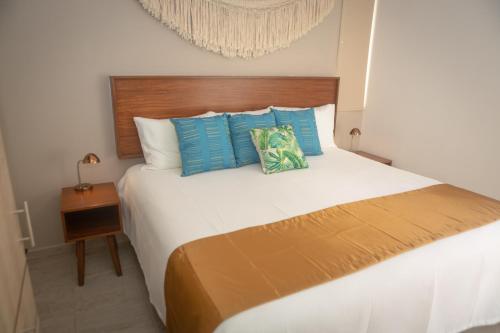 a bedroom with a large white bed with blue pillows at Casa Jaguar in Puerto Morelos