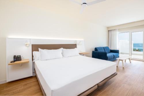 a white bedroom with a bed and a blue chair at Playamojácar in Mojácar