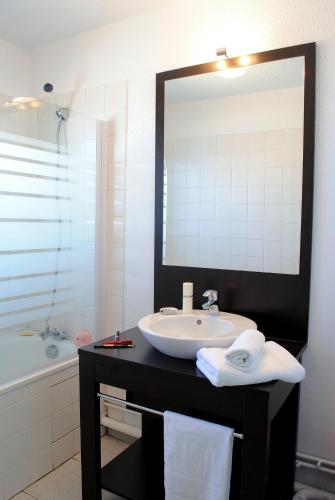 une salle de bain avec un lavabo, un miroir et une baignoire dans l'établissement Résidence Néméa Les Gourbets, à Mimizan-Plage