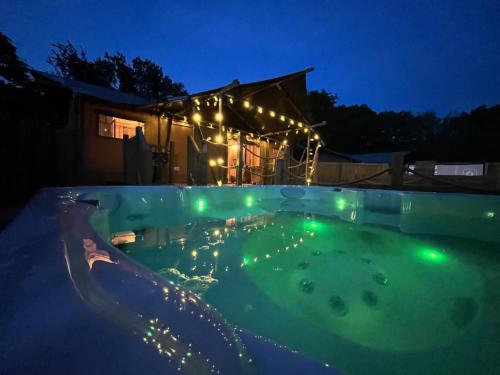 a swimming pool at night with lights in it at Lion King Safari Tent in Tenby