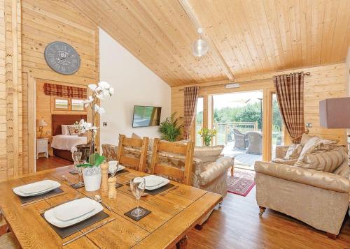 a living room with a wooden table and a clock at Gadlas Park Holiday Cabins in Ellesmere