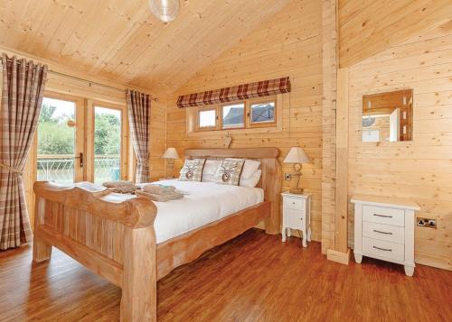 - une chambre avec un lit dans une cabane en rondins dans l'établissement Gadlas Park Holiday Cabins, à Ellesmere