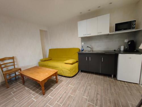 a small kitchen with a yellow couch and a table at Auberge Le Chata in Saint-Georges-de-Didonne