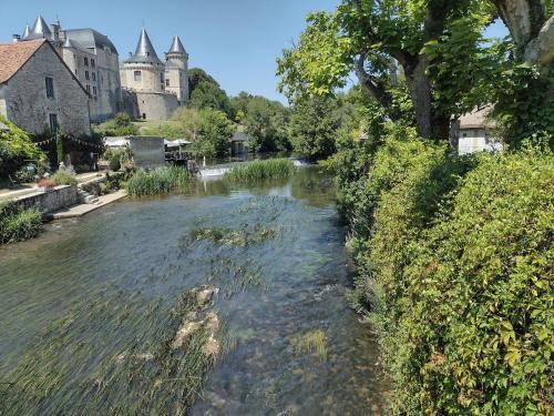 a river in a town with a castle in the background at La Maison des Roses 1-Bed House in Genouille in Génouillé