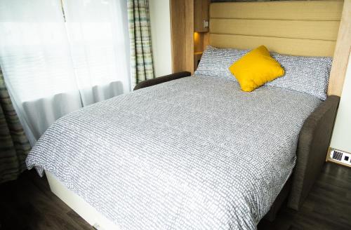 a bed with a yellow pillow on top of it at Benvoulin Bothy - luxury pod with stunning views in Oban