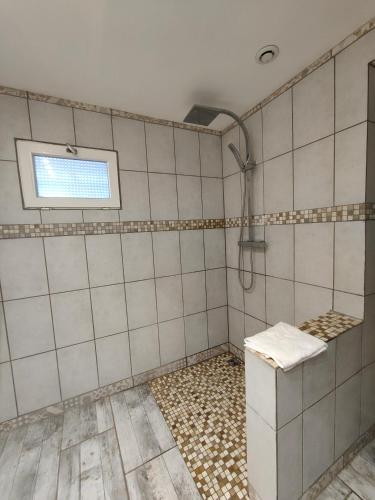 a white tiled bathroom with a shower and a window at Auberge Le Chata in Saint-Georges-de-Didonne