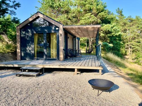 a tiny house with a deck and a black stool at Domki na Kaszubach z banią jacuzzi - Gołubie - Sikorska Dolina III in Stara Sikorska Huta