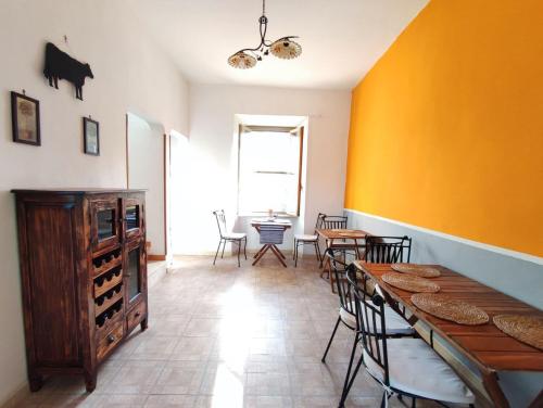 uma sala de jantar com mesa e cadeiras e uma parede amarela em Eco House San Michele em San Michele