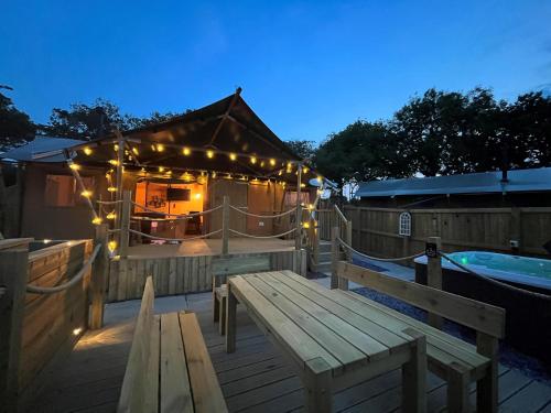 a deck with a wooden bench and a hot tub at Jungle Book Safari Tent in Tenby