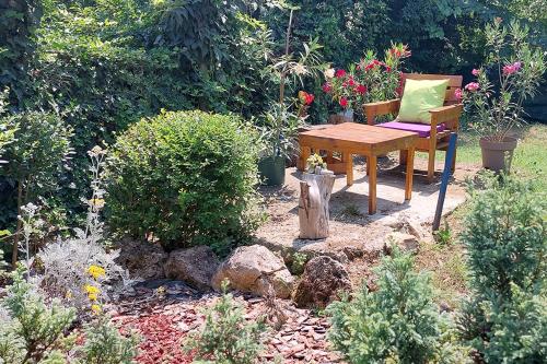 a garden with a wooden table and a chair and flowers at Villa Ramonda in Dolna Matka