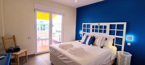 een blauwe slaapkamer met een groot bed en een blauwe muur bij Blue & Yellow Penthouse with Terrace at Balaia Mar in Albufeira