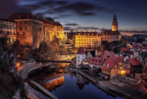 a city at night with a river and buildings at Belcanto Apartments in Český Krumlov