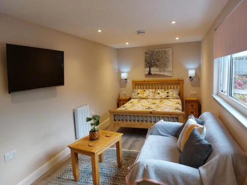 een slaapkamer met een bed, een bank en een tv bij Southwell Home Stay in Southwell