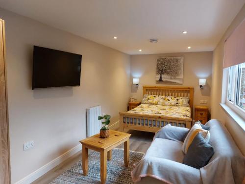 een slaapkamer met een bed, een bank en een tv bij Southwell Home Stay in Southwell