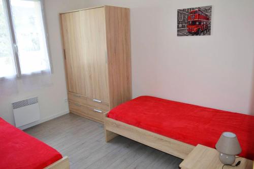 um quarto com uma cama vermelha e um armário de madeira em Maison de 3 chambres avec vue sur la mer jardin clos et wifi a Saint Laurent sur Mer em Saint-Laurent-sur-Mer