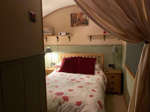 a bedroom with a bed with a red pillow on it at Brook the Shepherd Hut in Saltash
