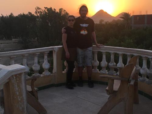 a man and woman standing on a balcony at sunset at Sakkara pyramid inn hotel in Cairo