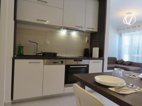 una cocina con armarios blancos y una mesa de madera con un asterisco en Apartman Prestige, en Pašman