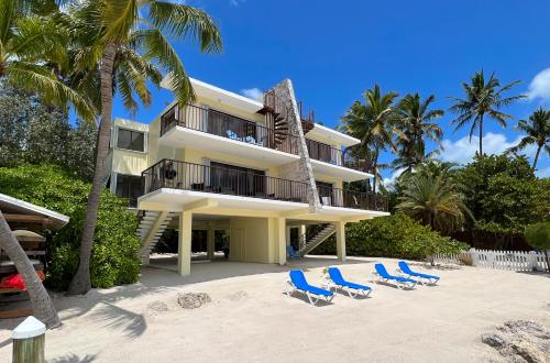 a beach with a pool, chairs, and a beach umbrella at Pines & Palms Resort in Islamorada