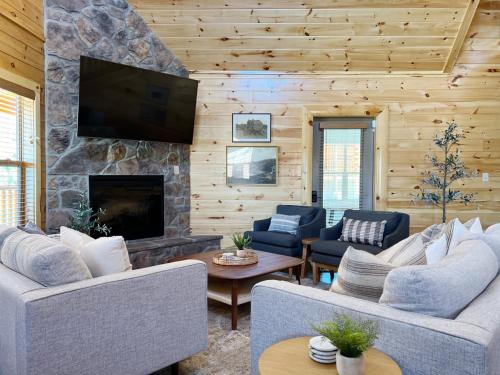 a living room with couches and a stone fireplace at Sweet Tea Timber Indoor Pool Hot Tub in Pigeon Forge