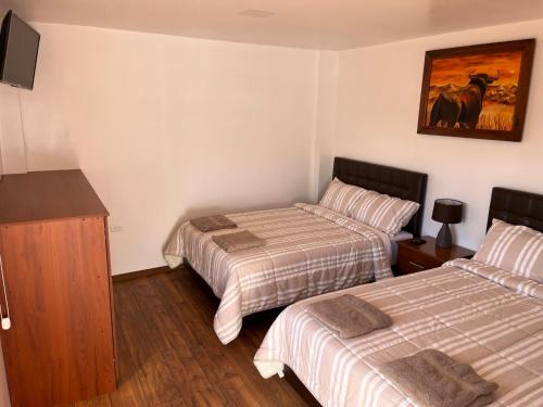 a hotel room with two beds and a tv at Mi Margarita Chalets in Alausí