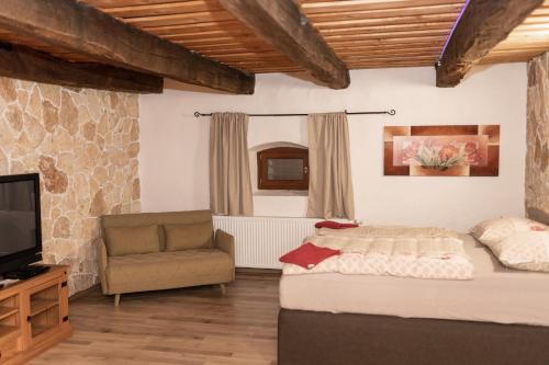 a bedroom with a bed and a chair and a television at GRANÁRIUM in Jablonov nad Turnou