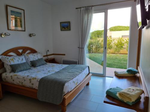 een slaapkamer met een bed en een glazen schuifdeur bij Chambres d'hôtes B&B La Bergeronnette avec piscine couverte chauffée in Bizanet