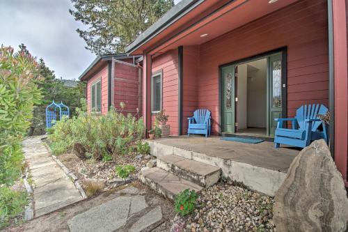 a red house with two blue chairs on a patio at Oceanfront Point Arena House with Lovely Deck! in Point Arena