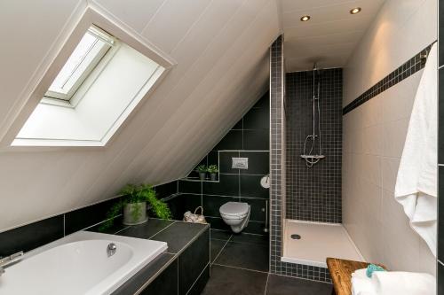 een badkamer met een ligbad en een toilet bij Brinkzate - De Brink in Dwingeloo